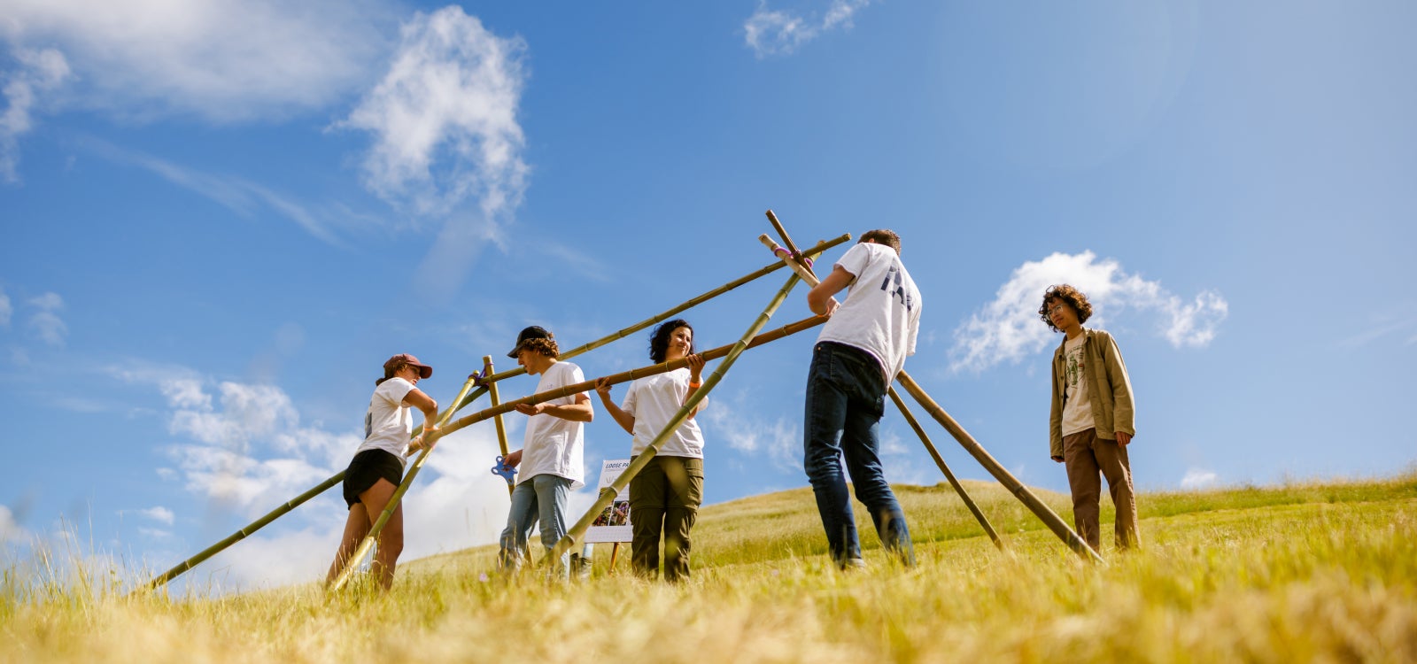 Students in a field building a structure.