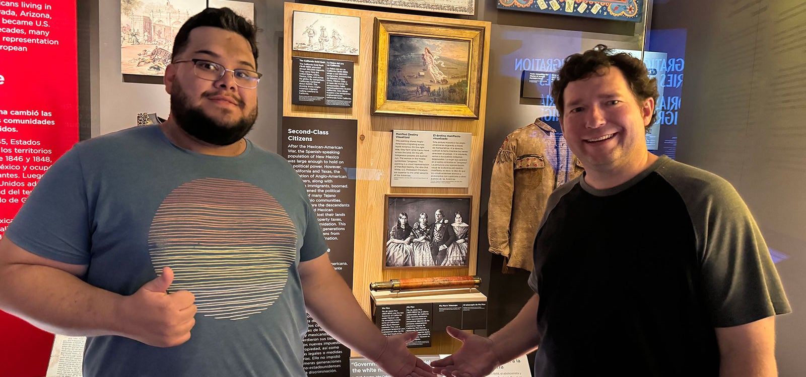 Two men stand in front of a gallery of historical images.