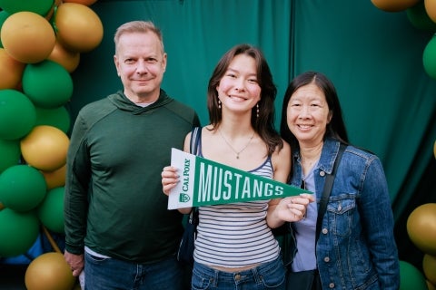 Student with their parents holding Cal Poly banner.