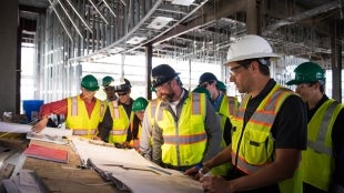 Group of students looking at construction plans together. 