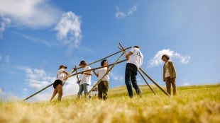 Students in a field building a structure.