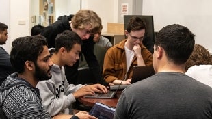 Students surrounding a computer. 