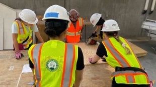 Four attendees of Girls Build Summer Academy work learn to use a power tool