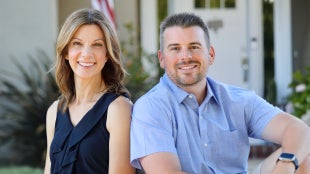 Portrait shot of couple sitting back to back looking straight ahead. 