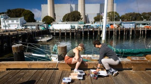 SURP engineering students deploy tide and wave gauges on one of the piers in Morro Bay.
