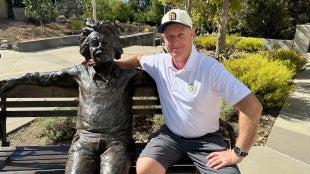 Alum Aaron Dodell poses with bronze Einstein statue in front of the Warren J. Baker Center for Science and Mathematics