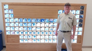 Mark Kent in front of a periodic table of elements