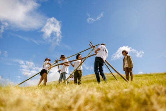 Students in a field building a structure.