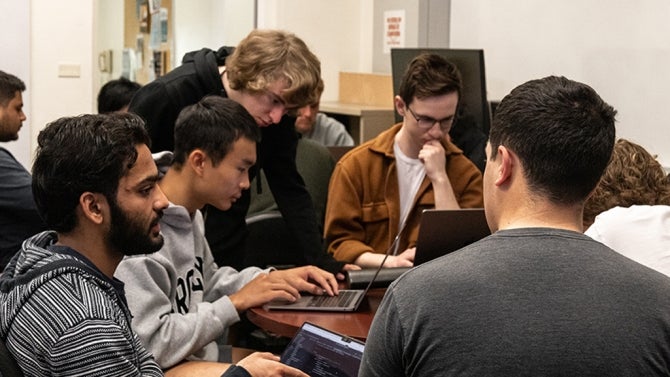 Students surrounding a computer. 