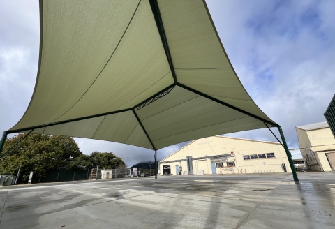 The Dathe Family Student Project Center, featuring a custom-designed shade sail, offers a collaborative workspace on a paved area adjacent to the Hangar. 